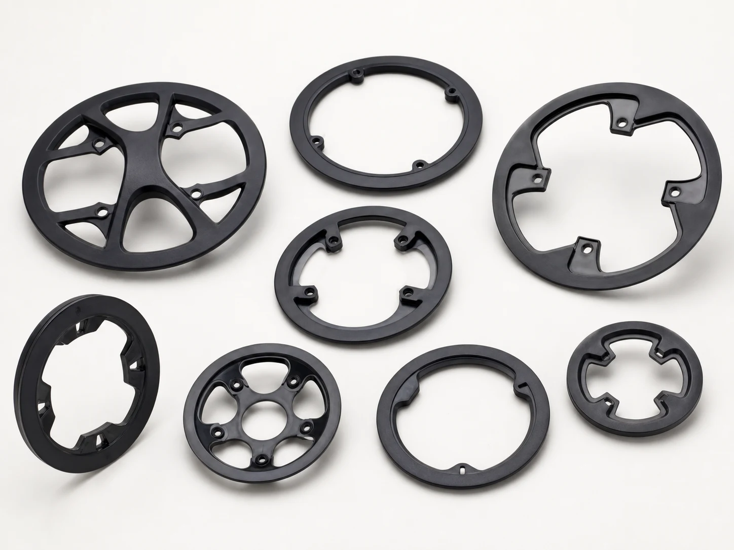 Unbranded bicycle chain guards, covers and spiders on a neutral studio background