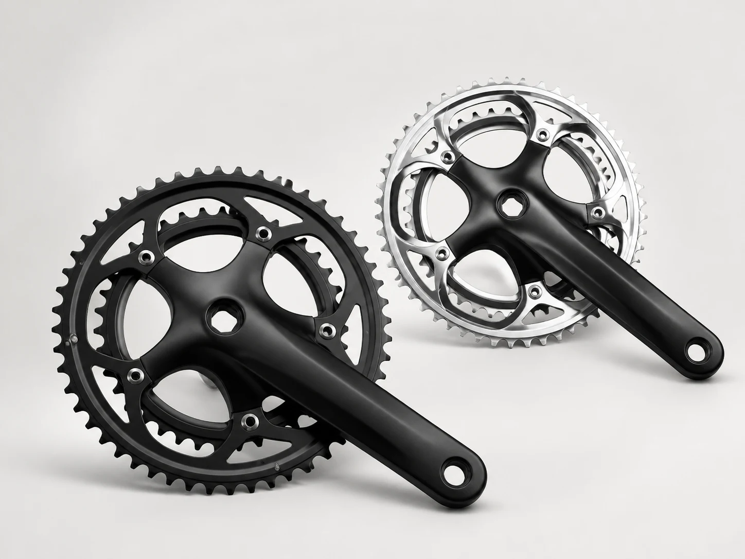 Unbranded black and silver road bicycle cranksets on a neutral studio background
